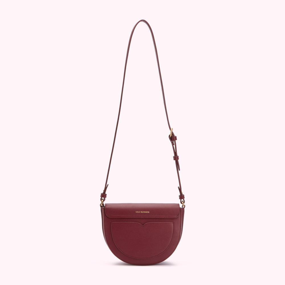 Burgundy half-moon crossbody bag with gold hardware and adjustable strap against a white background.
