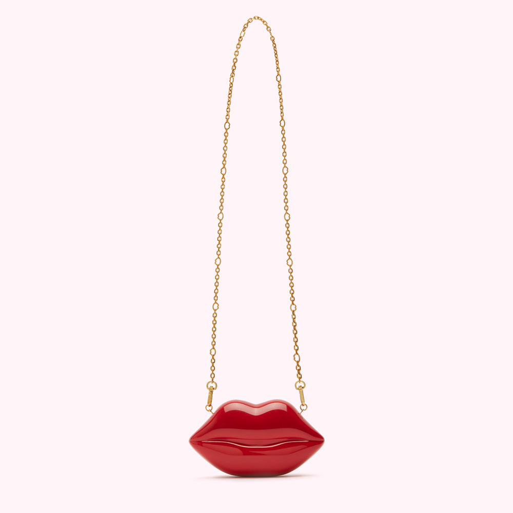 Red lip-shaped clutch with gold chain strap.
