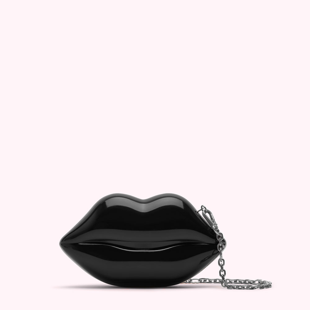 Black lip-shaped clutch with silver chain strap against a white background.
