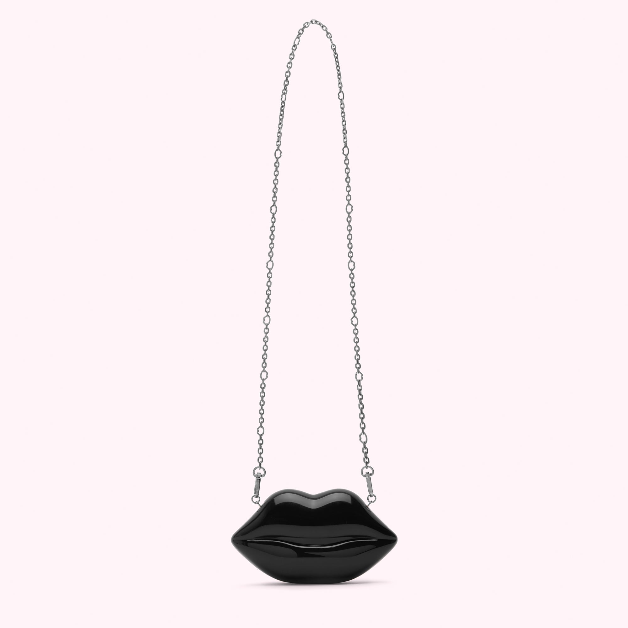 Black lip-shaped crossbody bag with a silver chain strap against a white background.
