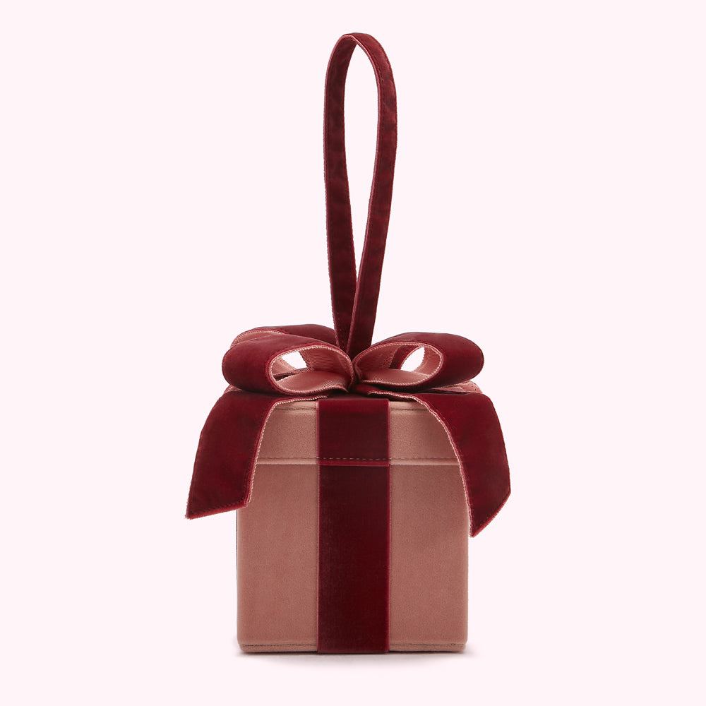 A blush pink velvet gift box with a burgundy velvet bow and handle.
