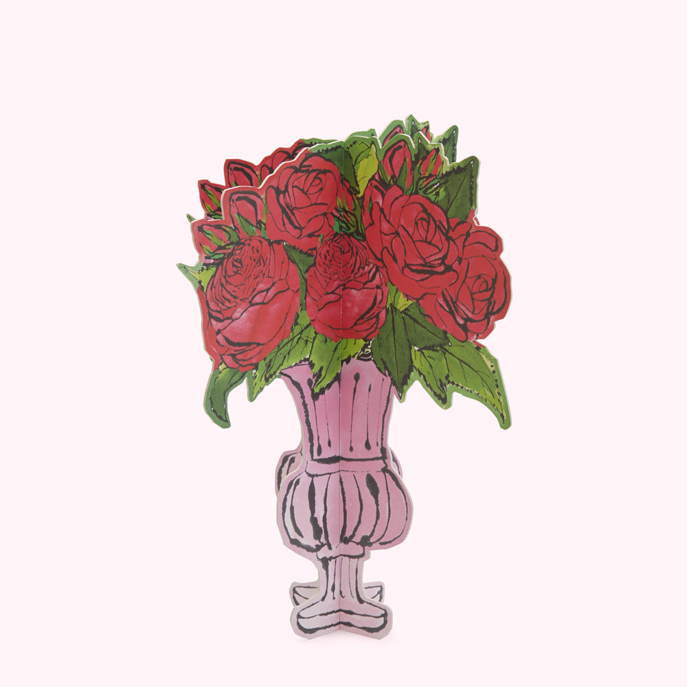 A pink vase of red roses against a white background.
