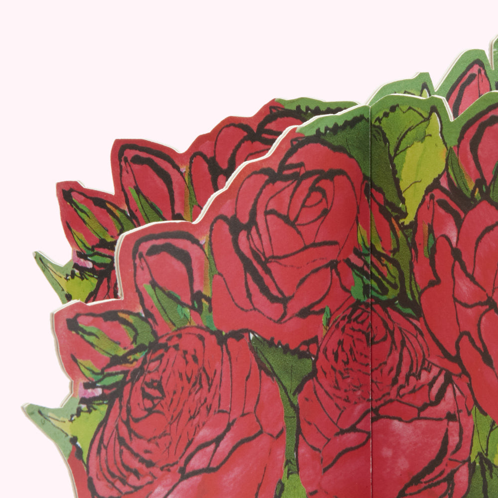 Close-up of a pop-up card featuring a bouquet of red roses with green leaves, the background is white.
