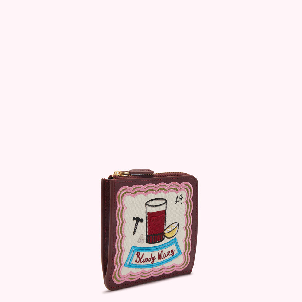 Burgundy leather zip-around wallet with an embroidered illustration of a Bloody Mary cocktail on an off-white background.