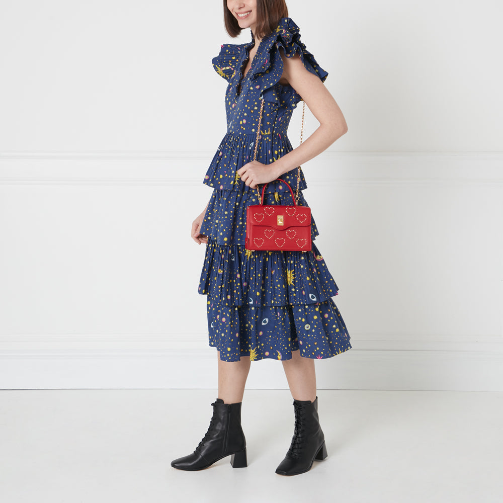 Woman in a blue dress holding a red heart-shaped handbag.