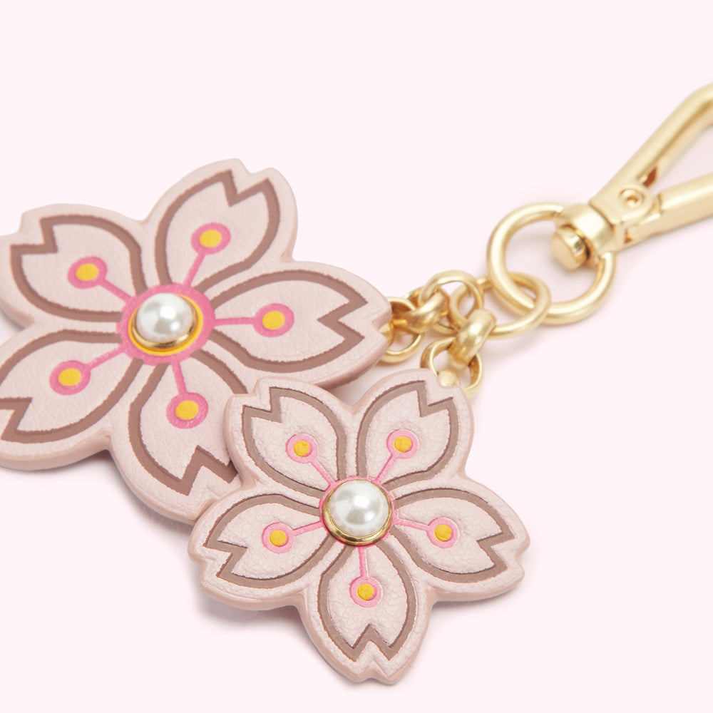Pink leather keychain with two cherry blossom charms and gold hardware.
