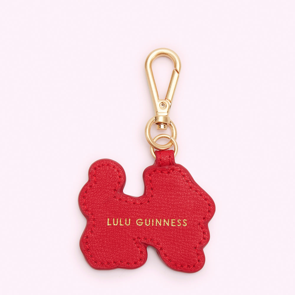 Red Lulu Guinness leather keychain in an abstract shape with gold-tone hardware.
