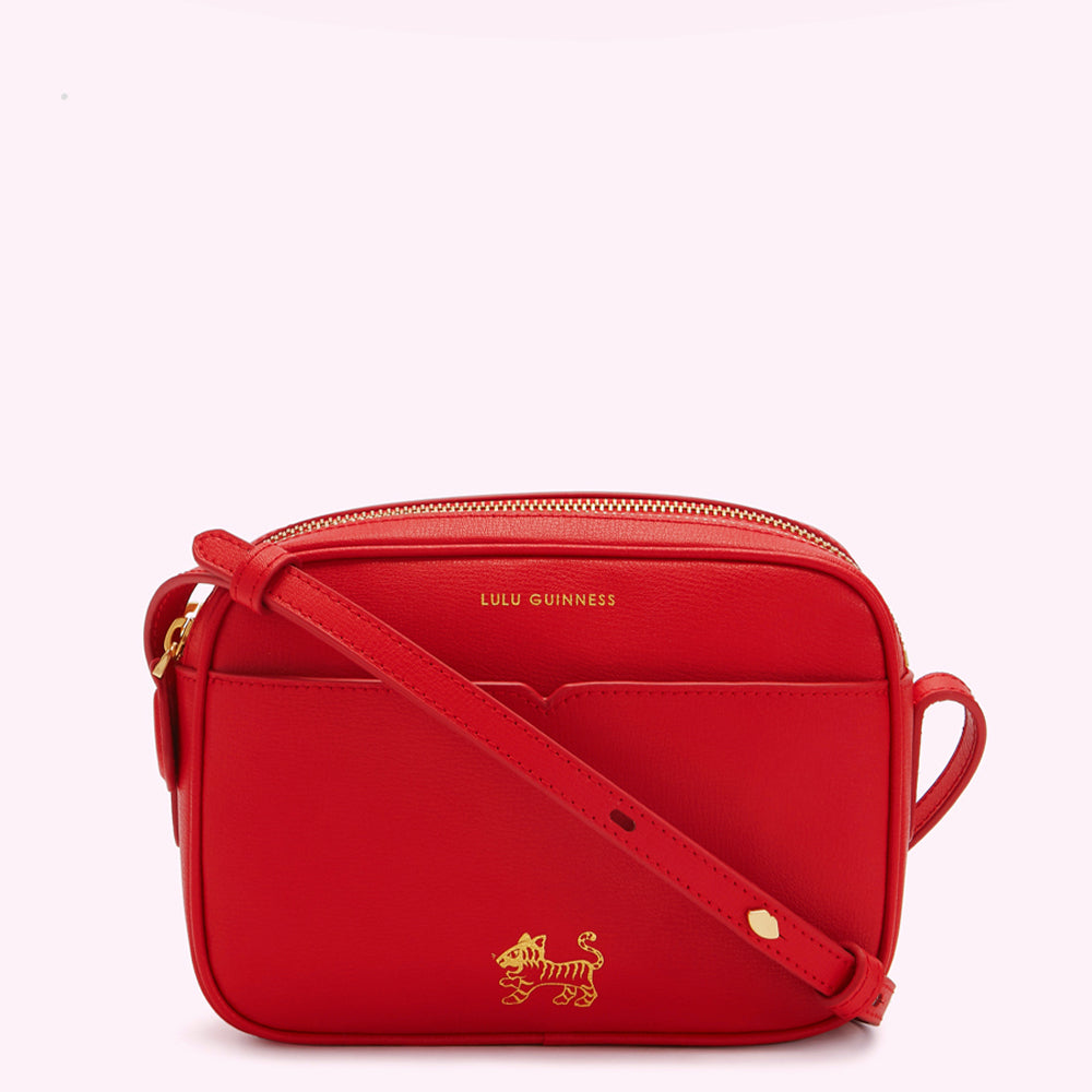 Red Lulu Guinness crossbody bag with gold tiger emblem.
