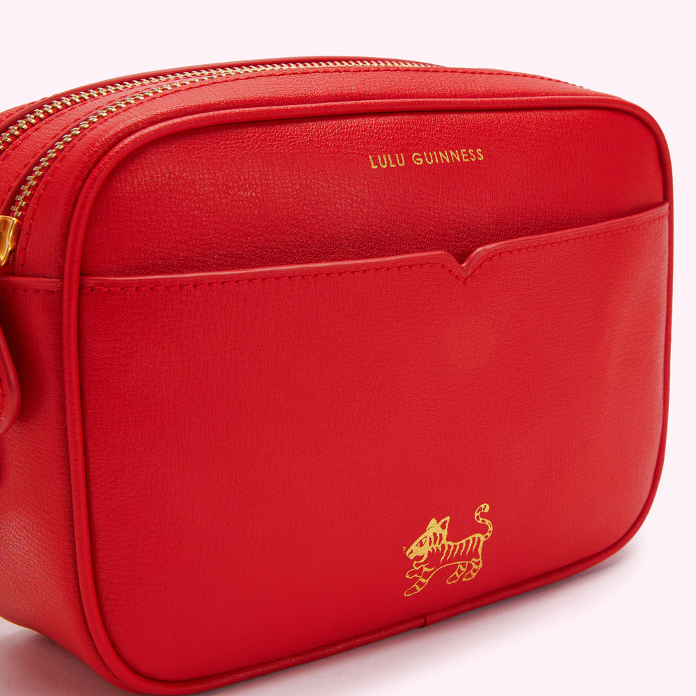 Red Lulu Guinness crossbody bag with gold zipper and tiger detail.

