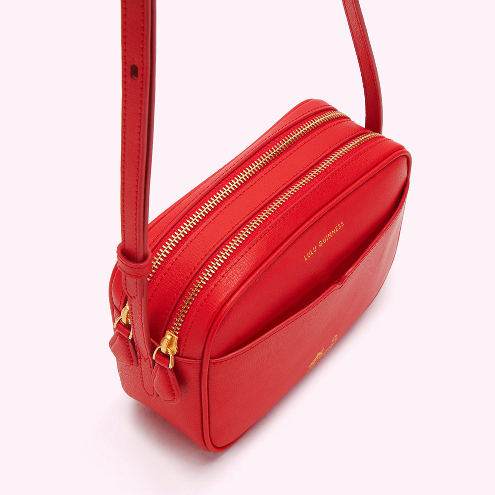 Red Lulu Guinness crossbody bag with gold zippers.
