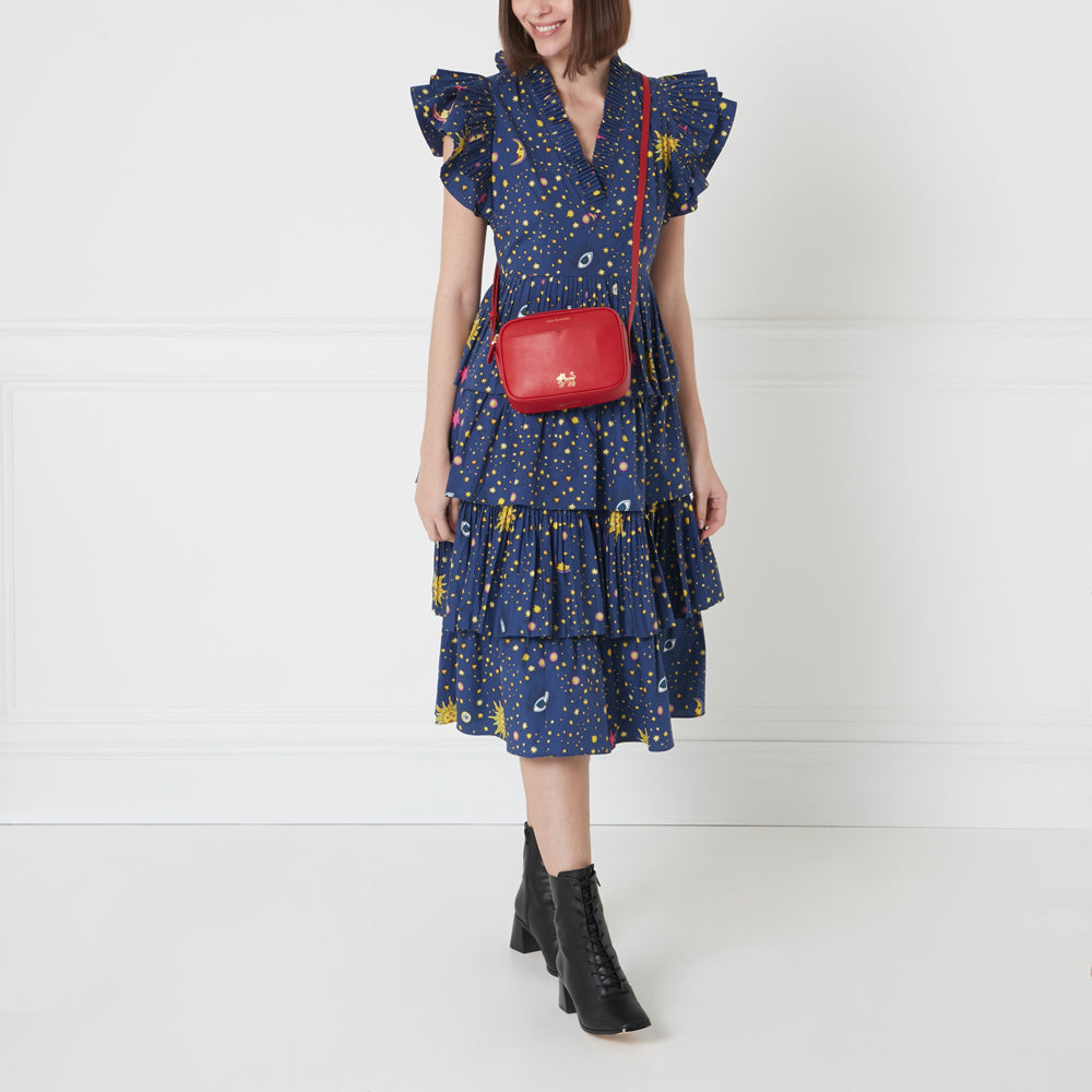 Woman in a blue dress with celestial print wearing black lace-up boots and a red crossbody bag.