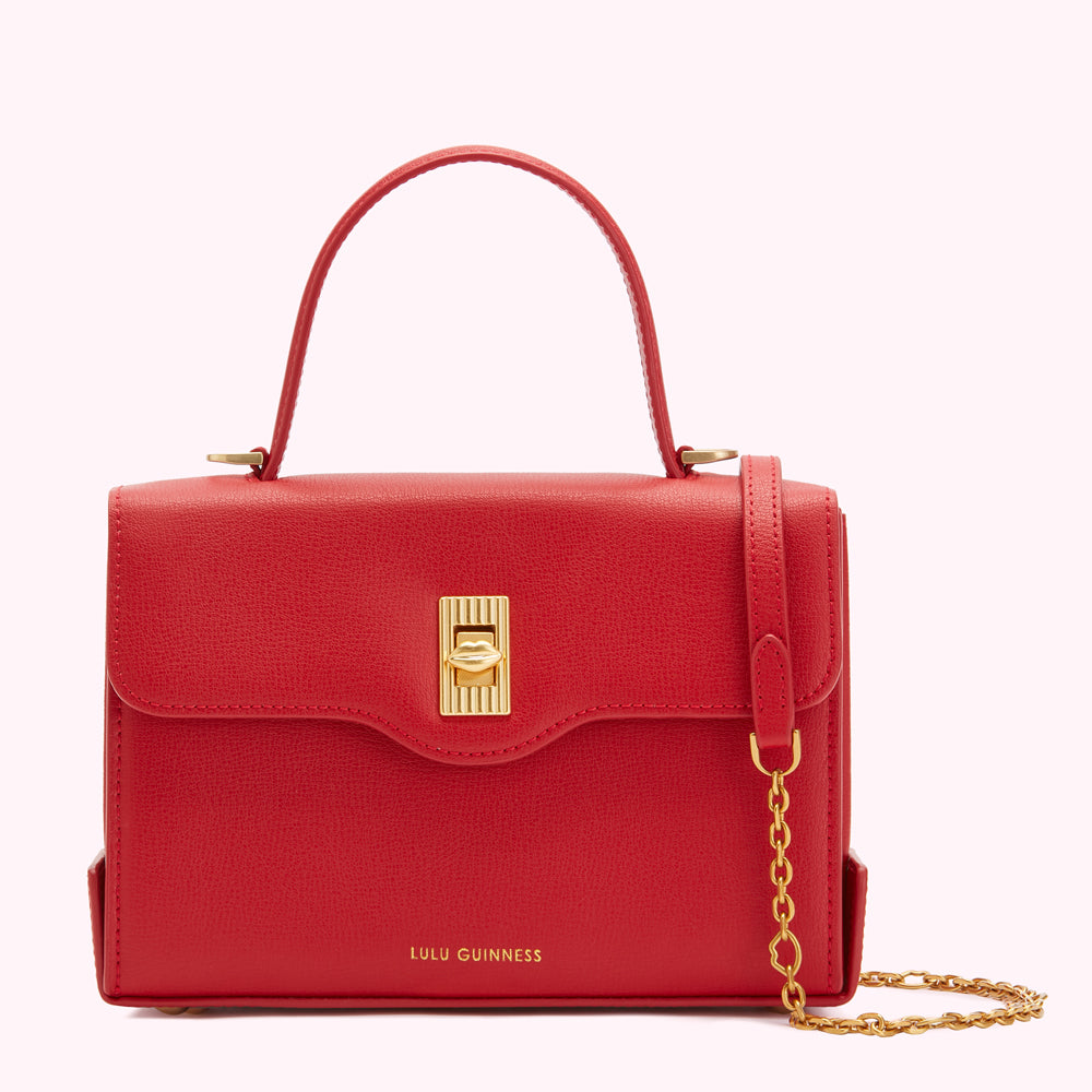 Red Lulu Guinness satchel bag with gold hardware and chain strap.
