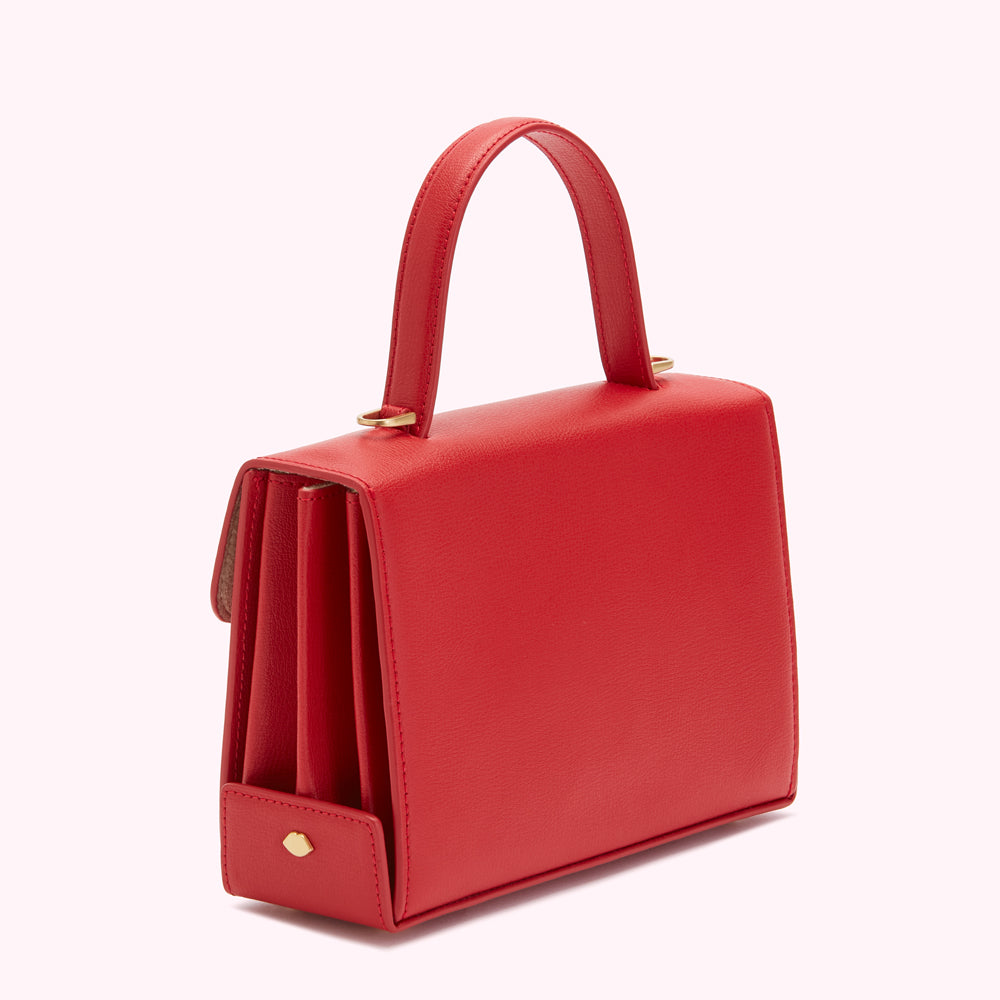 A red leather handbag with a top handle, shown against a white background.
