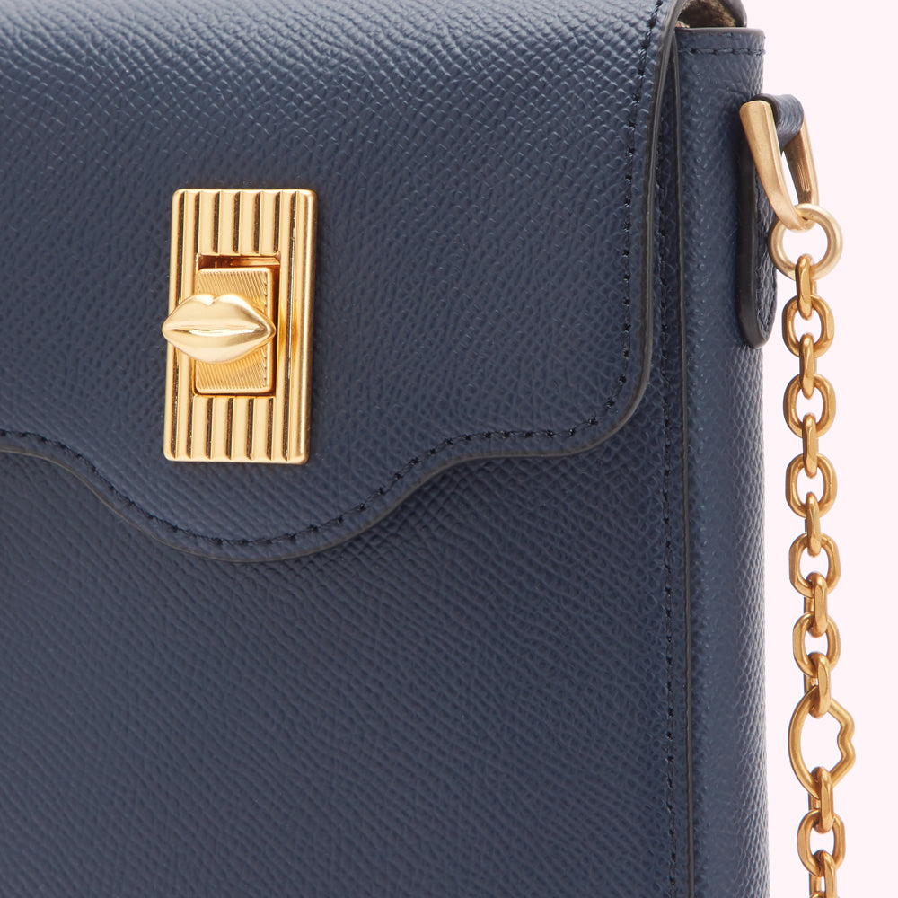 Close-up of a navy blue leather handbag with a gold lip-shaped clasp and gold chain strap.
