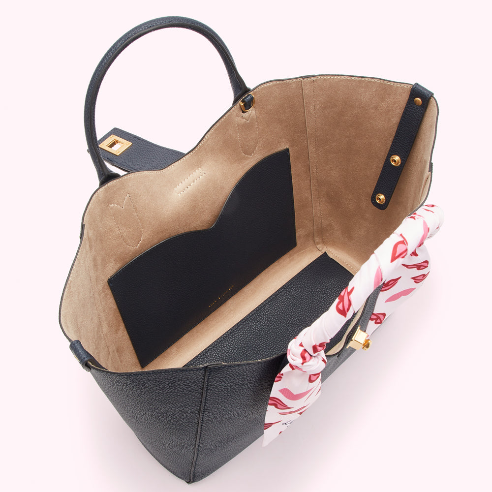 Open navy blue tote bag with beige interior and a pink and white scarf.
