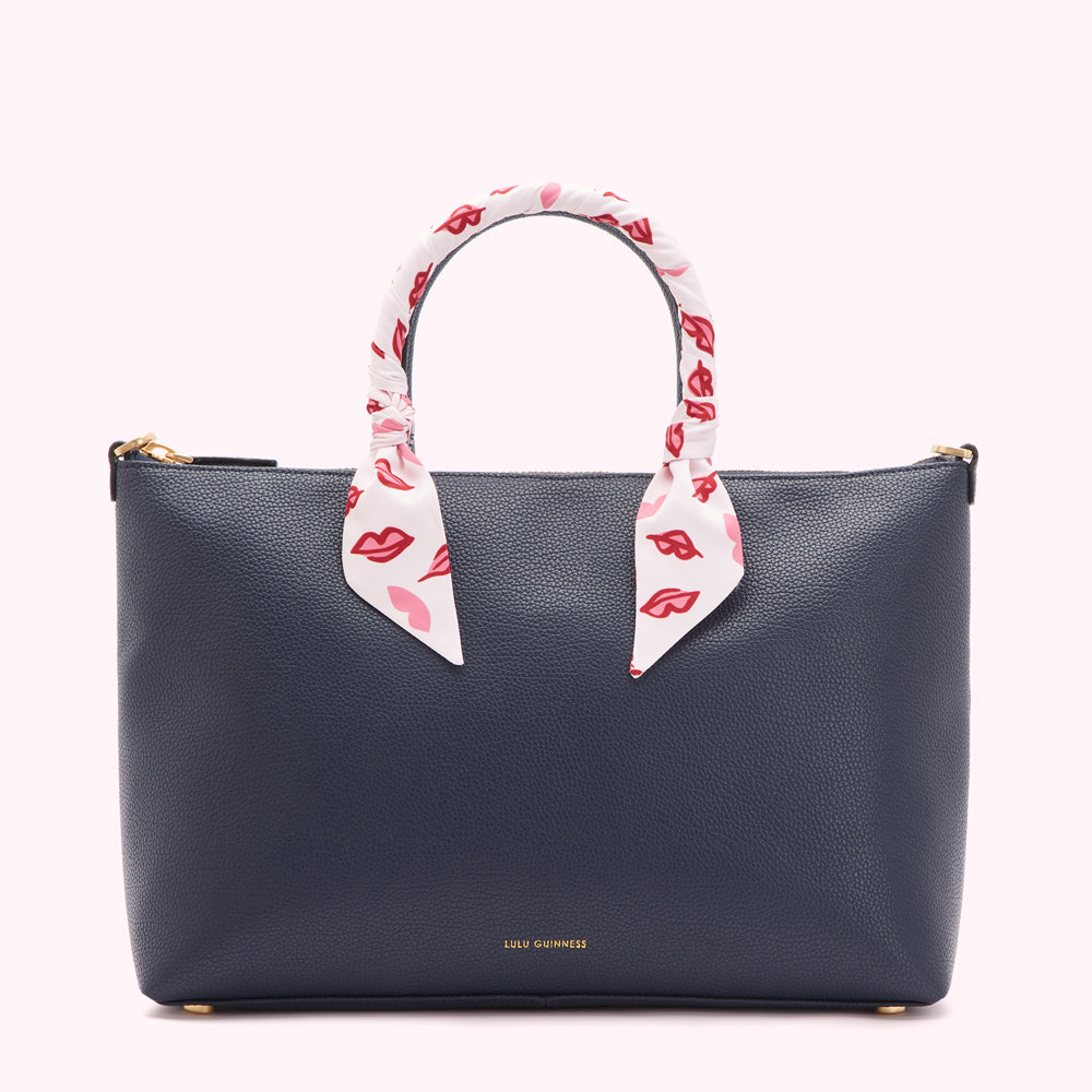Navy blue Lulu Guinness tote bag with a white and red lips patterned scarf handle.