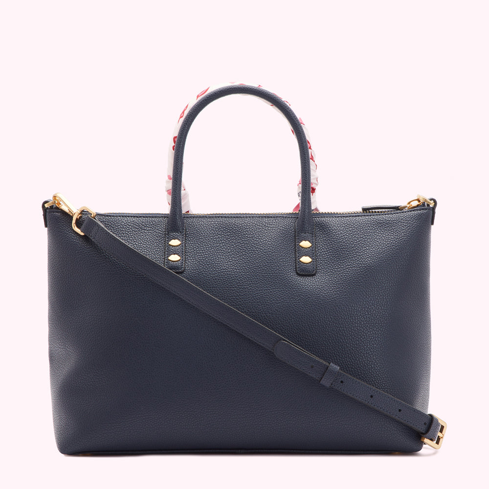 Dark blue leather tote bag with a white and red patterned handle and a long shoulder strap.