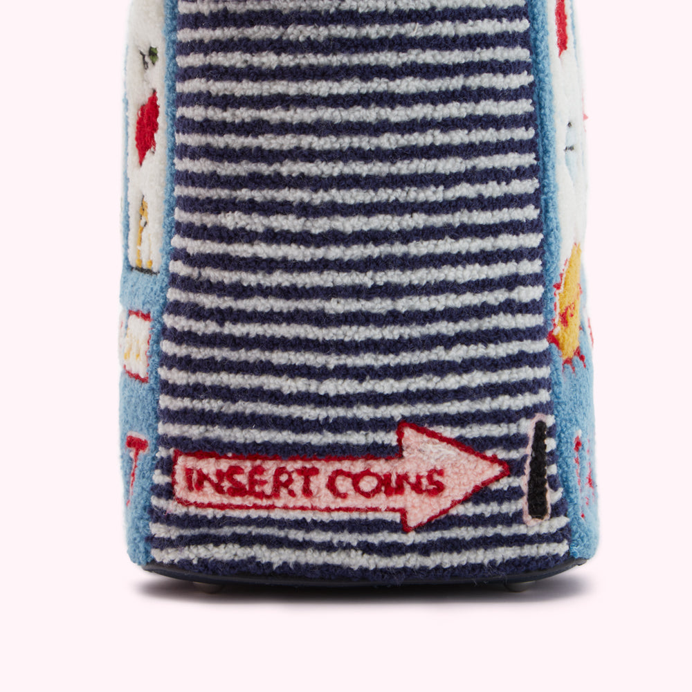 Close-up of a blue and white striped textile bag with embroidered details, including an arrow pointing to the text "INSERT COINS".