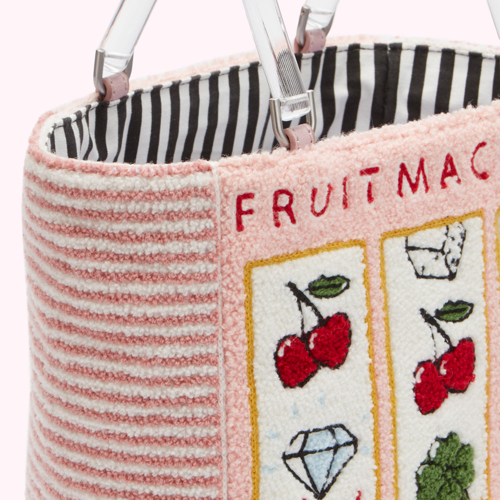 Close-up of a pink and white striped tote bag with embroidered fruit machine design and clear acrylic handles. The bag's lining is black and white striped.
