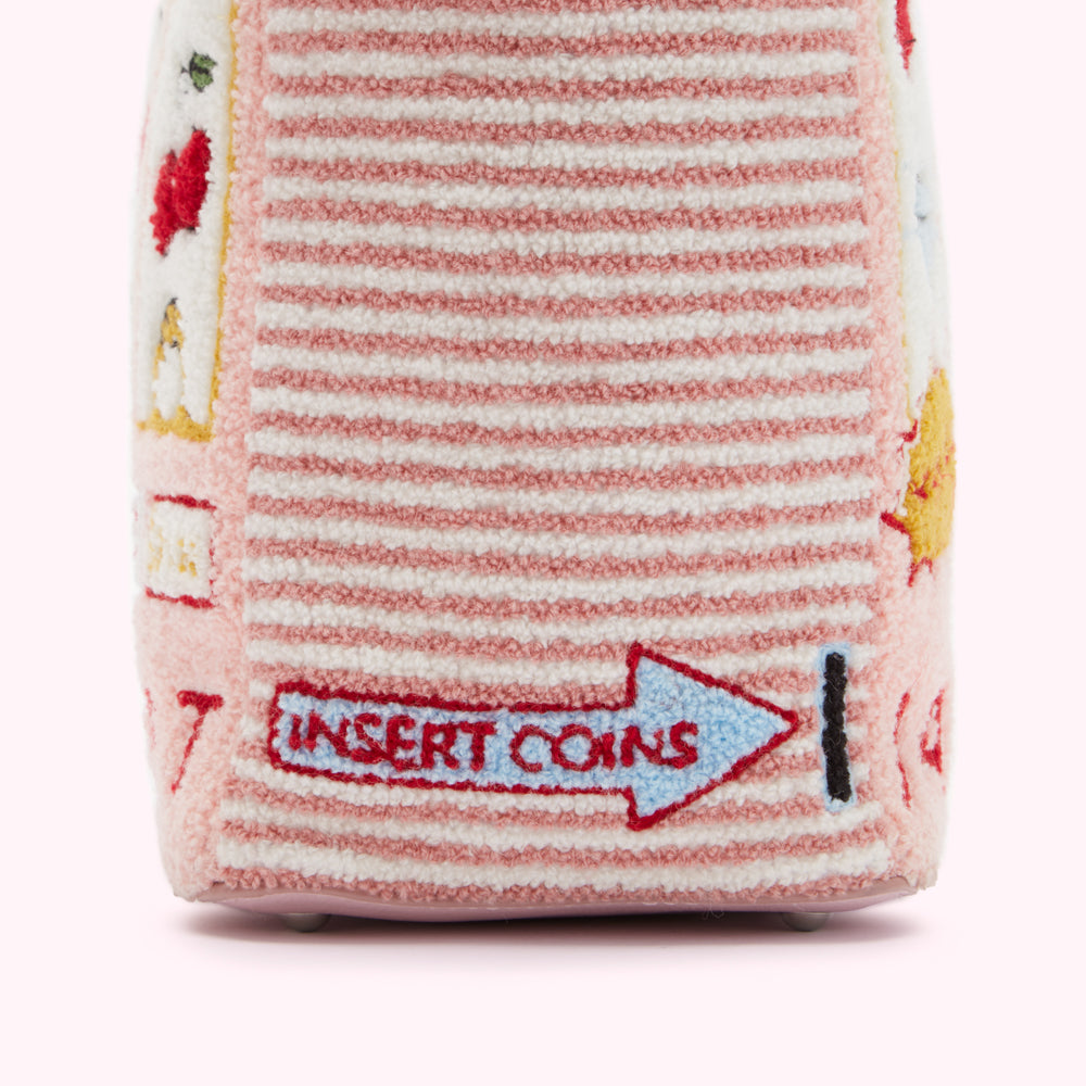 Close-up of a pink striped fabric bag with embroidered details, including an arrow pointing right with the words "Insert Coins".