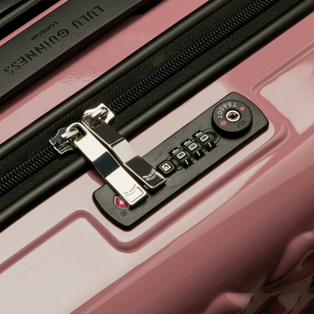 Close-up of a pink Lulu Guinness suitcase showing the TSA-approved combination lock and zipper.
