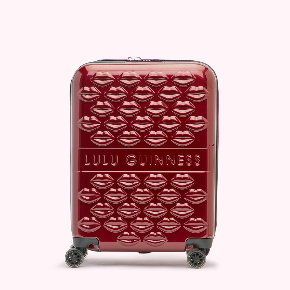 Red Lulu Guinness suitcase covered in embossed lips.
