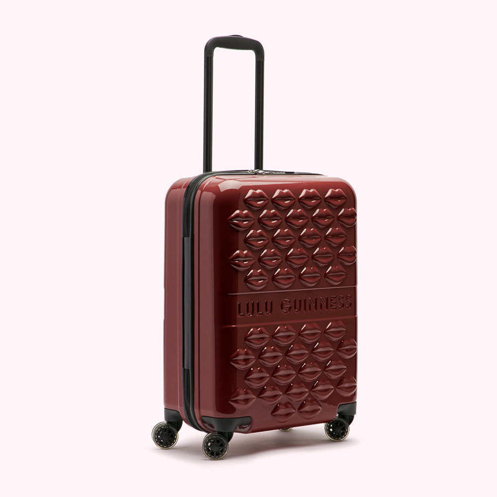 Burgundy Lulu Guinness suitcase with a lip print design.
