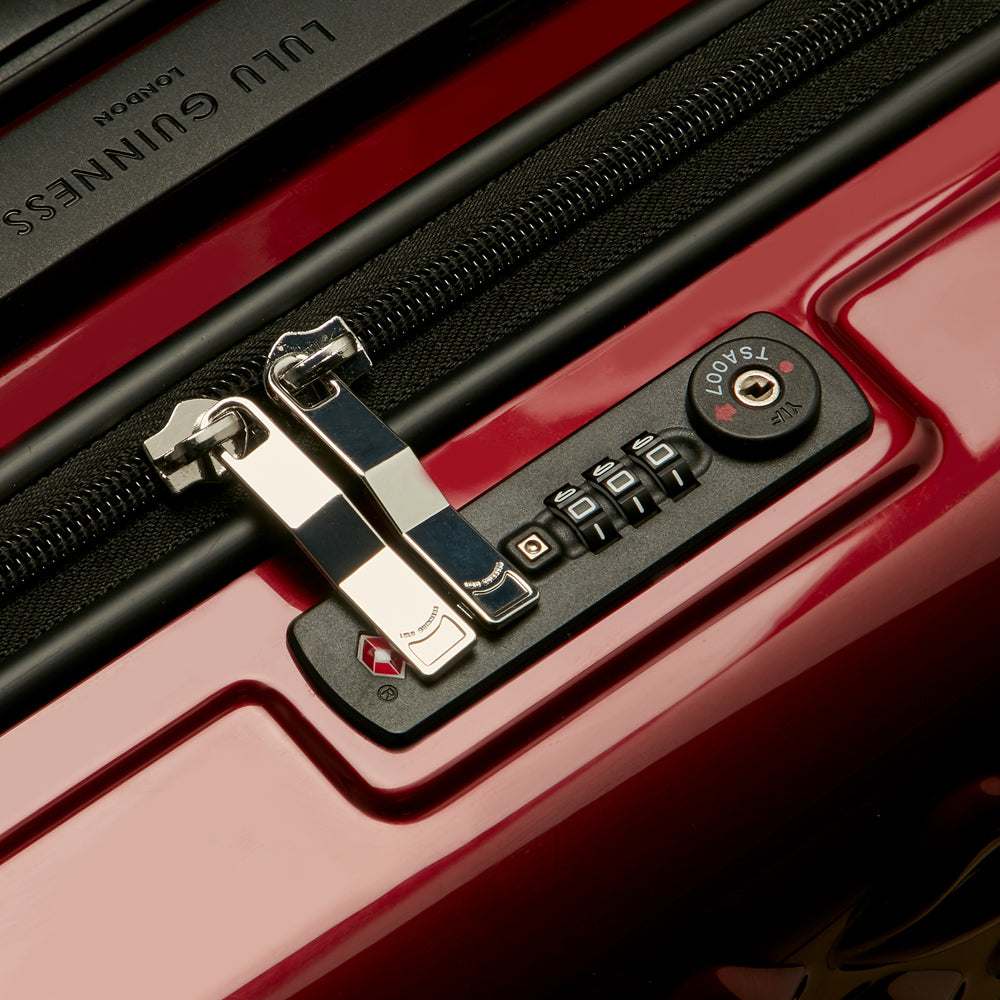 Close-up of a red Lulu Guinness suitcase's TSA-approved combination lock and zipper.