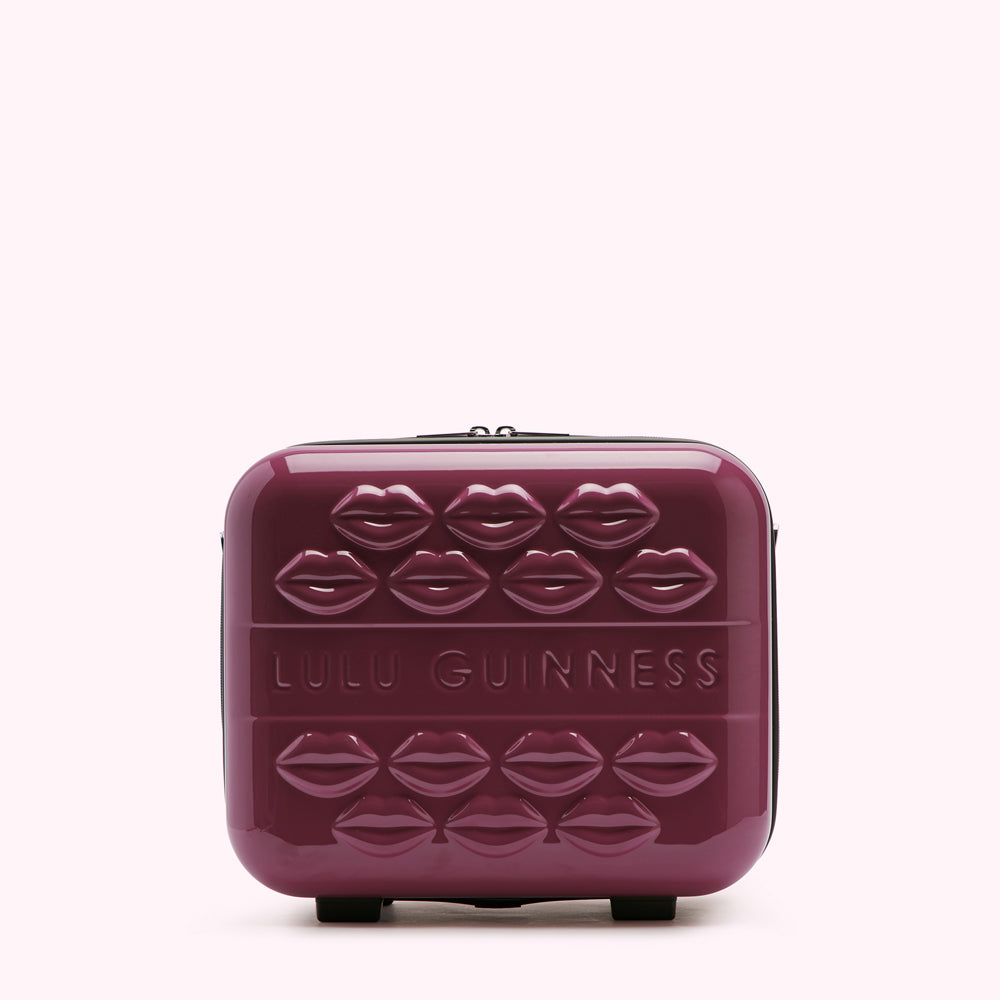 A burgundy Lulu Guinness rolling suitcase adorned with embossed lips.