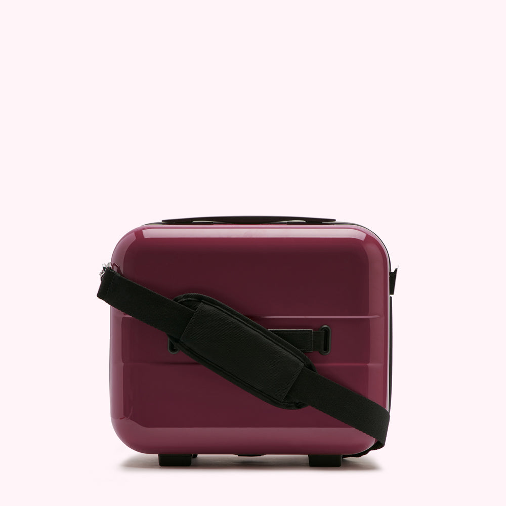 A maroon carry-on suitcase with a black shoulder strap against a white background.
