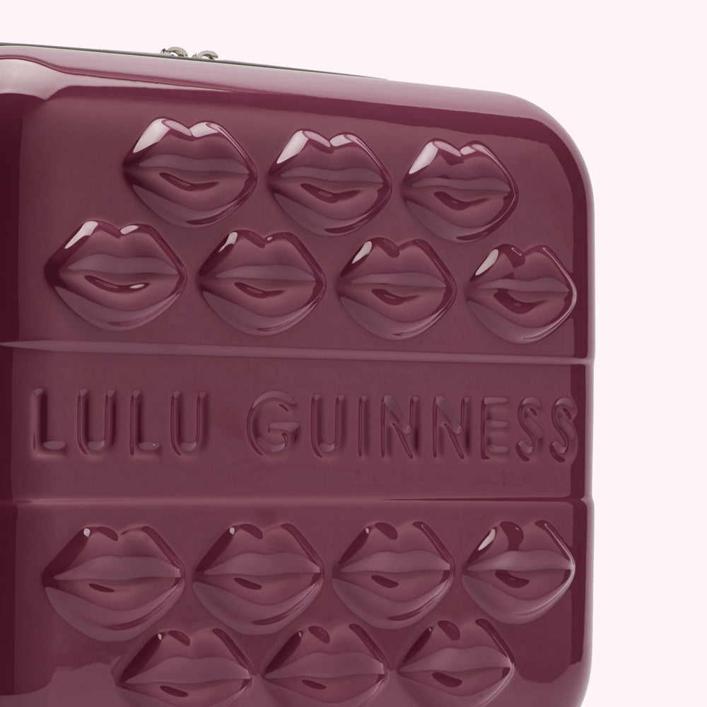 Close-up of a burgundy Lulu Guinness handbag with embossed lips and logo.
