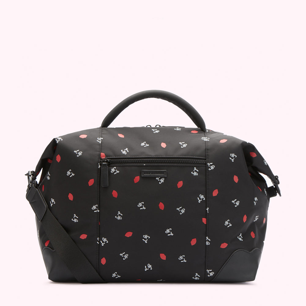 Black bag with red lips and white lettering pattern, black shoulder strap.

