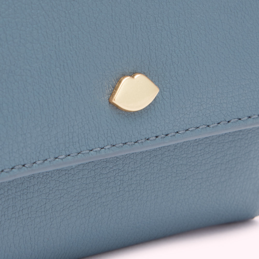 Close-up of a blue leather wallet with a gold lip-shaped detail.
