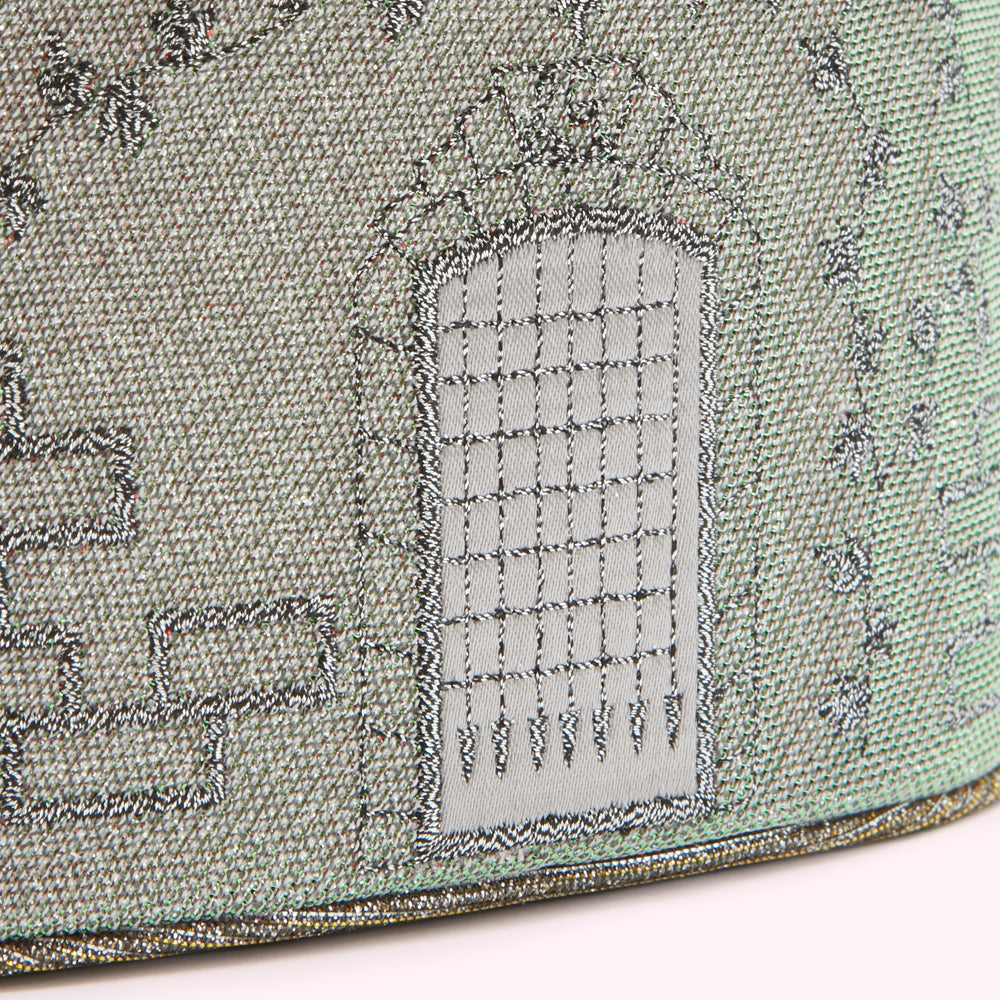 Close-up of a silver embroidered details, featuring a prominent stitched section resembling a gate or door.

