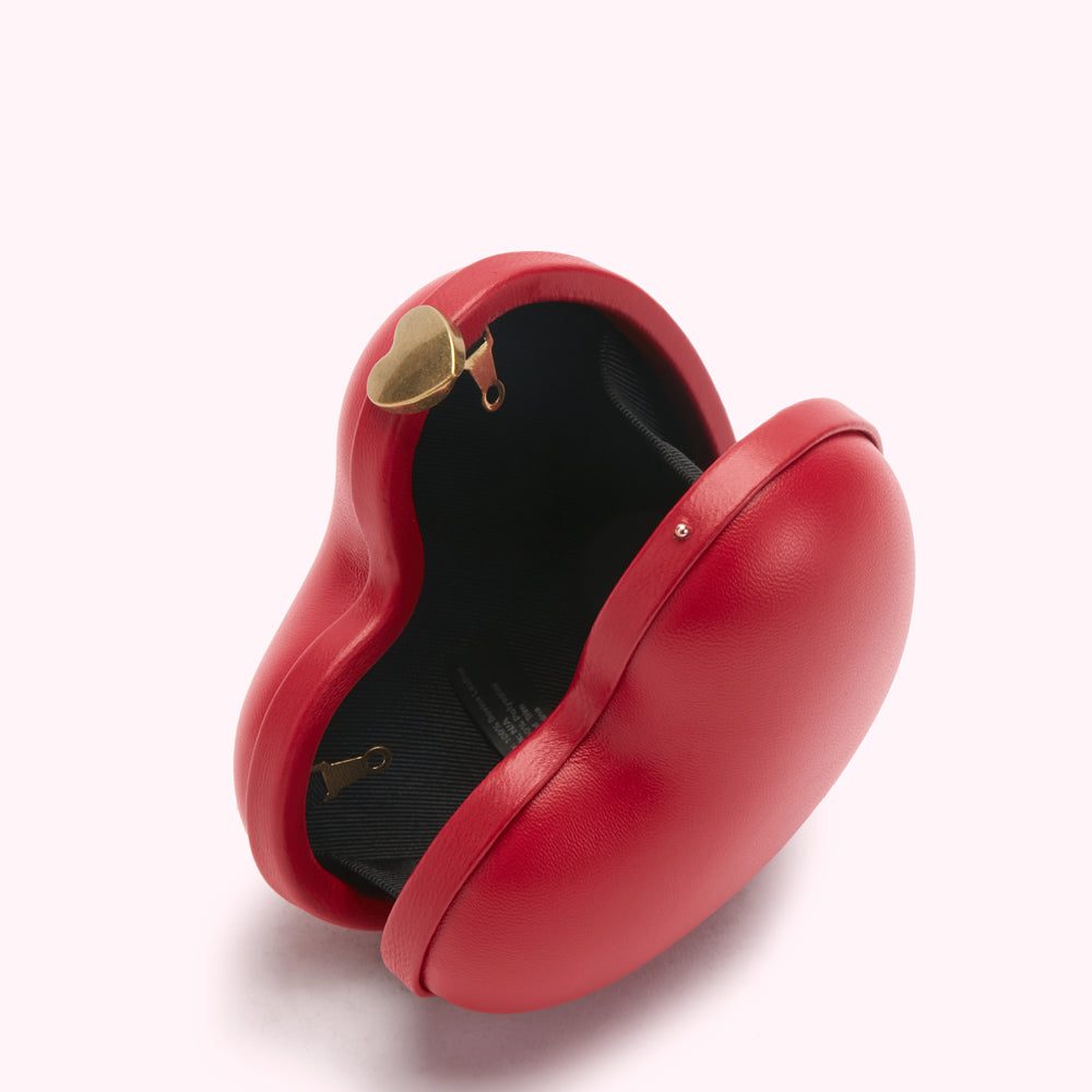 Red heart-shaped clutch open to reveal black interior and gold heart clasp.
