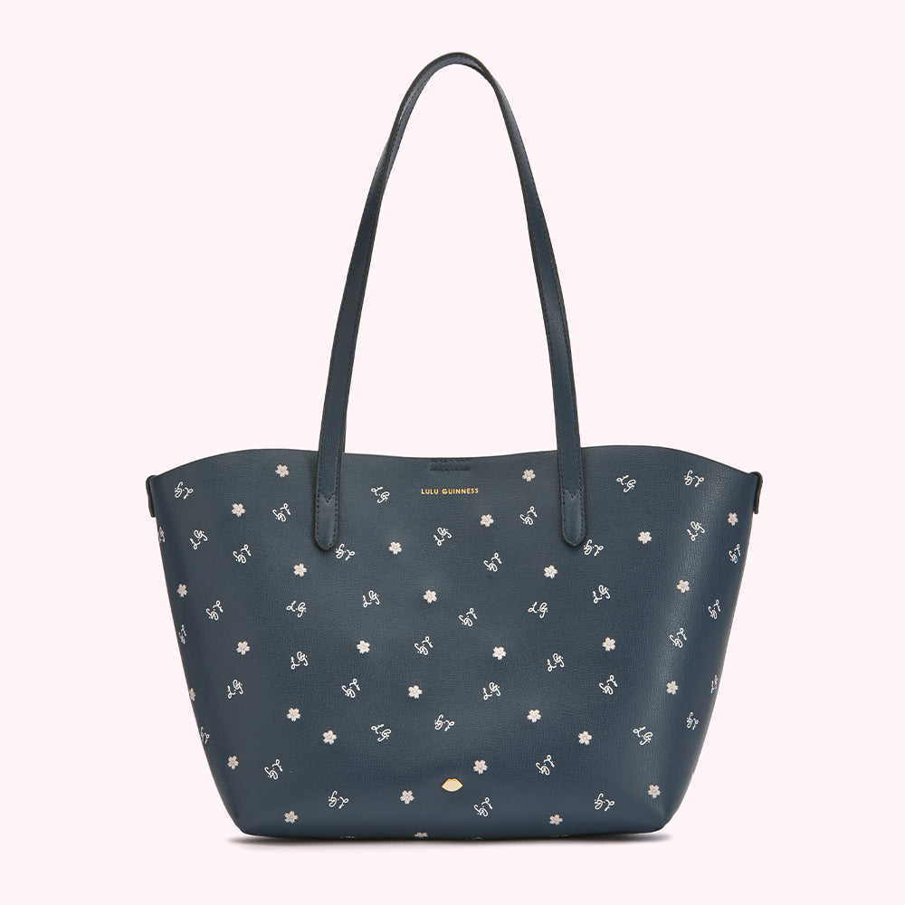 Navy blue tote bag with a small white flower pattern and the Lulu Guinness logo.

