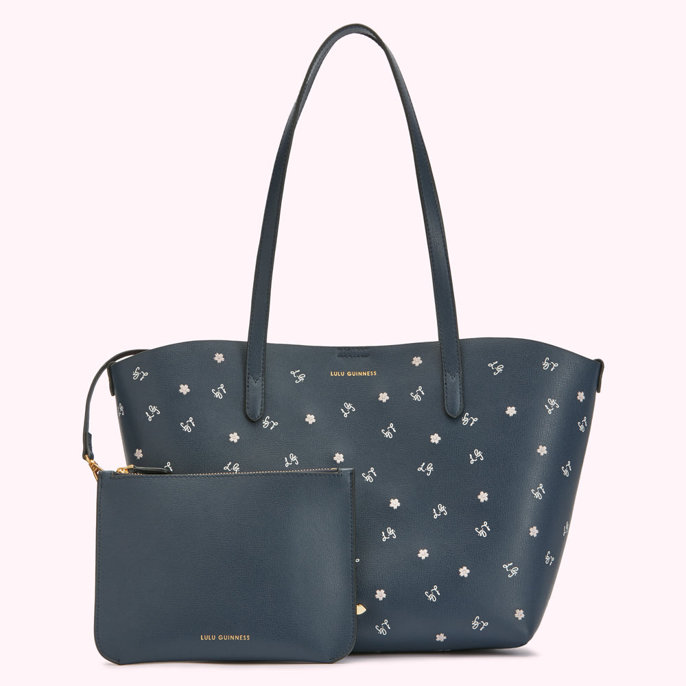Navy blue tote bag and matching pouch with a white floral and monogram pattern.