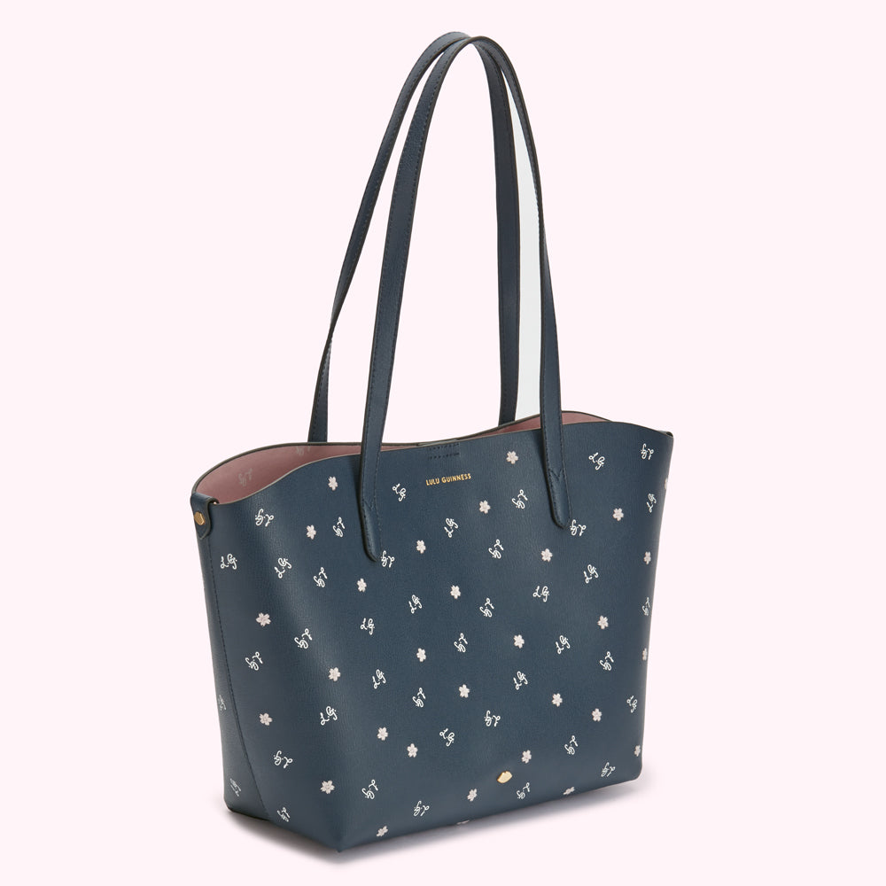 Navy blue tote bag with a pink interior and a repeating pattern of small white flowers and the Lulu Guinness logo.