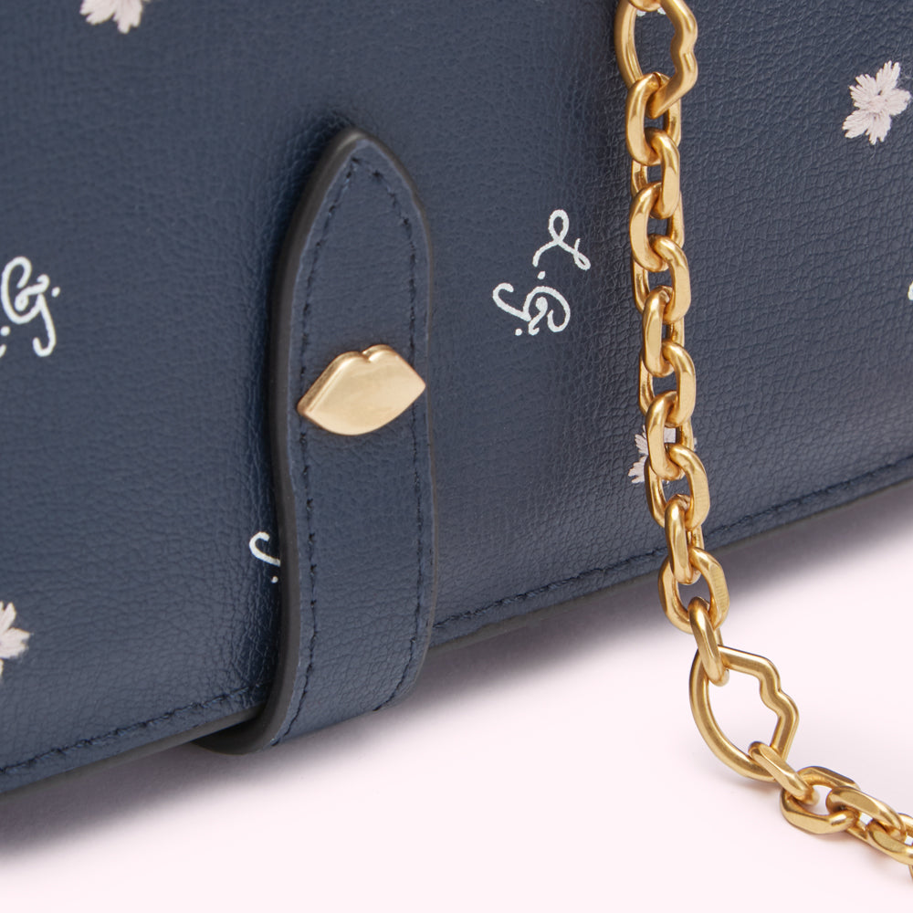 Close-up of a navy blue leather wallet with a gold chain and lip-shaped accents.