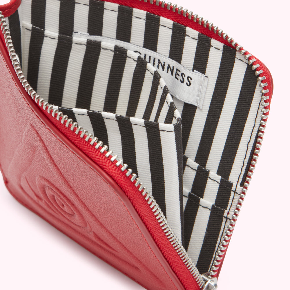 Red leather Guinness zip-around wallet open to reveal a black and white striped interior.

