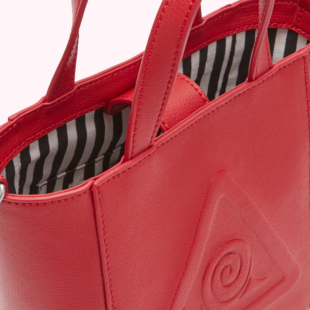 Close-up of a red leather tote bag with a black and white striped interior and embossed triangular logo.