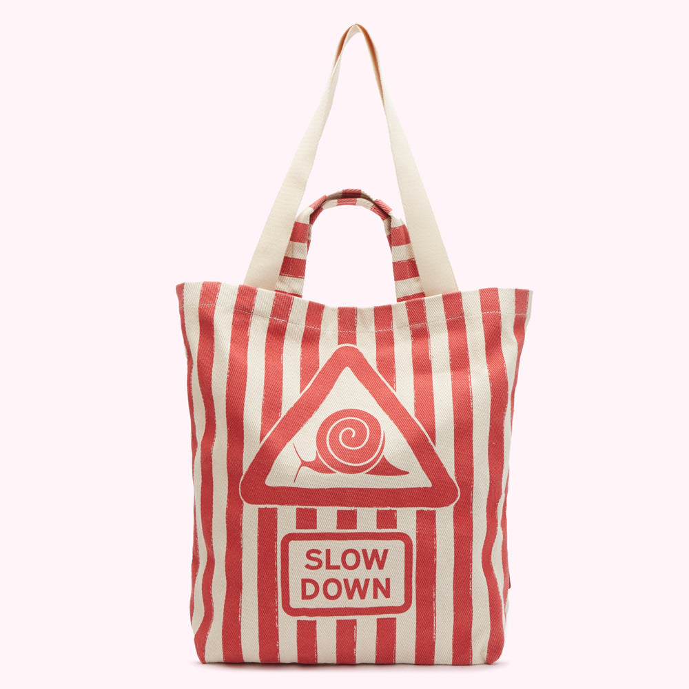 Red and white striped tote bag with a "Slow Down" graphic featuring a snail inside a triangle.
