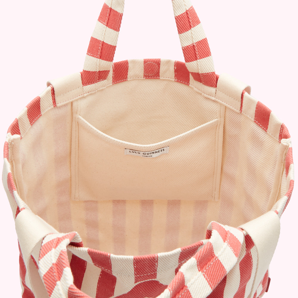 Inside of a coral and cream striped tote bag showing a small interior pocket and the Lulu Guinness London label.
