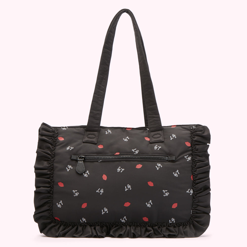 Black tote bag with ruffled trim and a lip print.