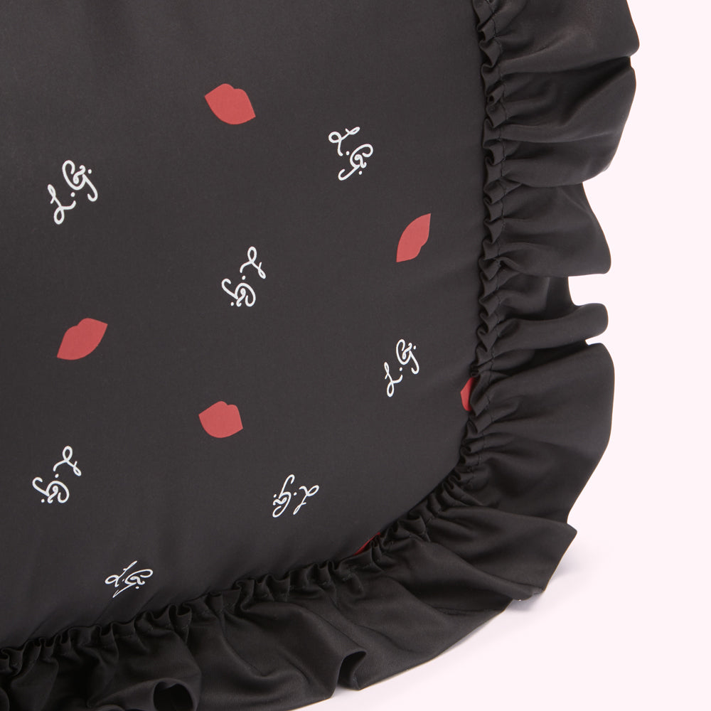 Black cushion with red lips and white script print, black ruffled trim.