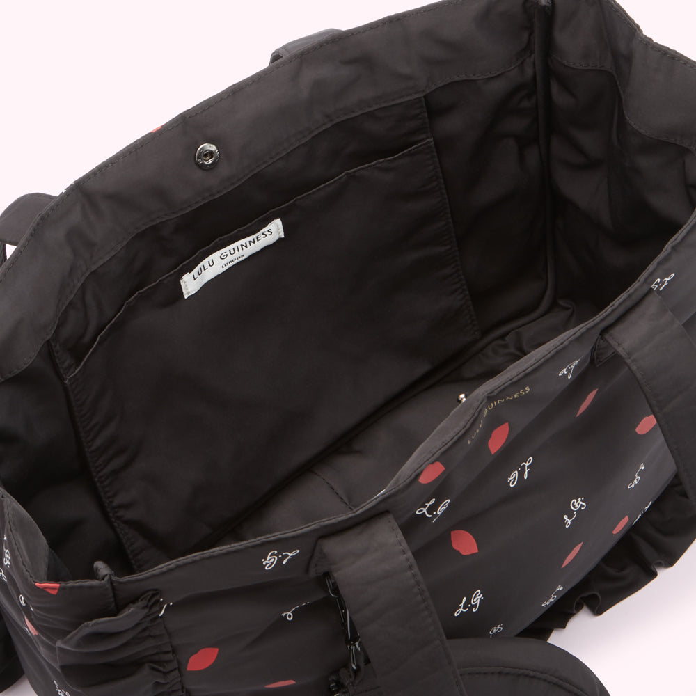 Inside of a black Lulu Guinness tote bag with red lips print.