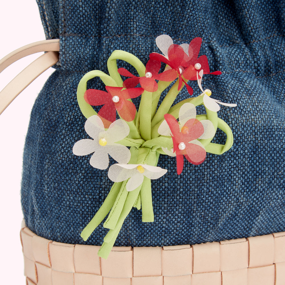 Close-up of a denim handbag adorned with a fabric flower bouquet.