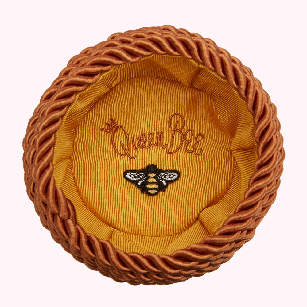 Orange braided hatbox with a mustard yellow interior, embroidered with "Queen Bee" and a small bee.