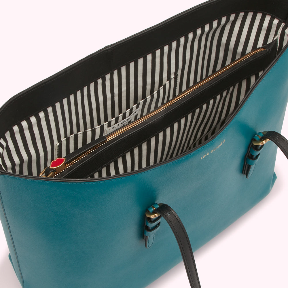 Teal Lulu Guinness tote bag open to reveal black and white striped interior with gold zipper.