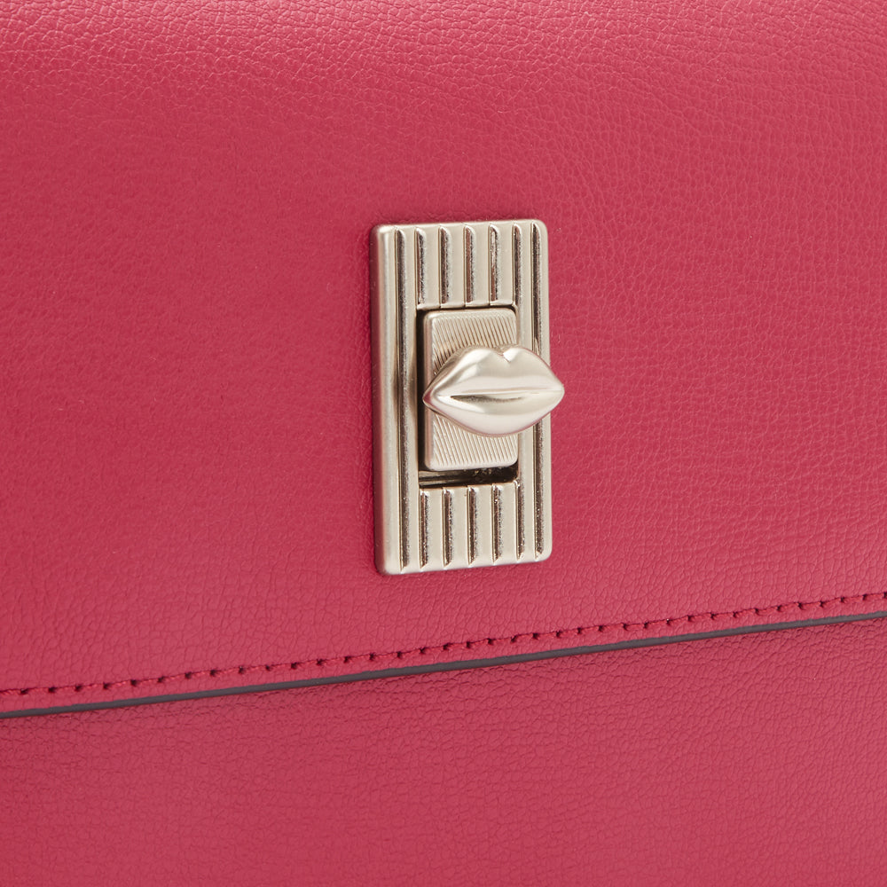 Close-up of a pink handbag's clasp, featuring a silver lip-shaped detail.
